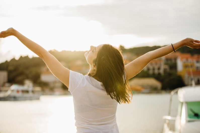 Young happy woman dancing under the sun.