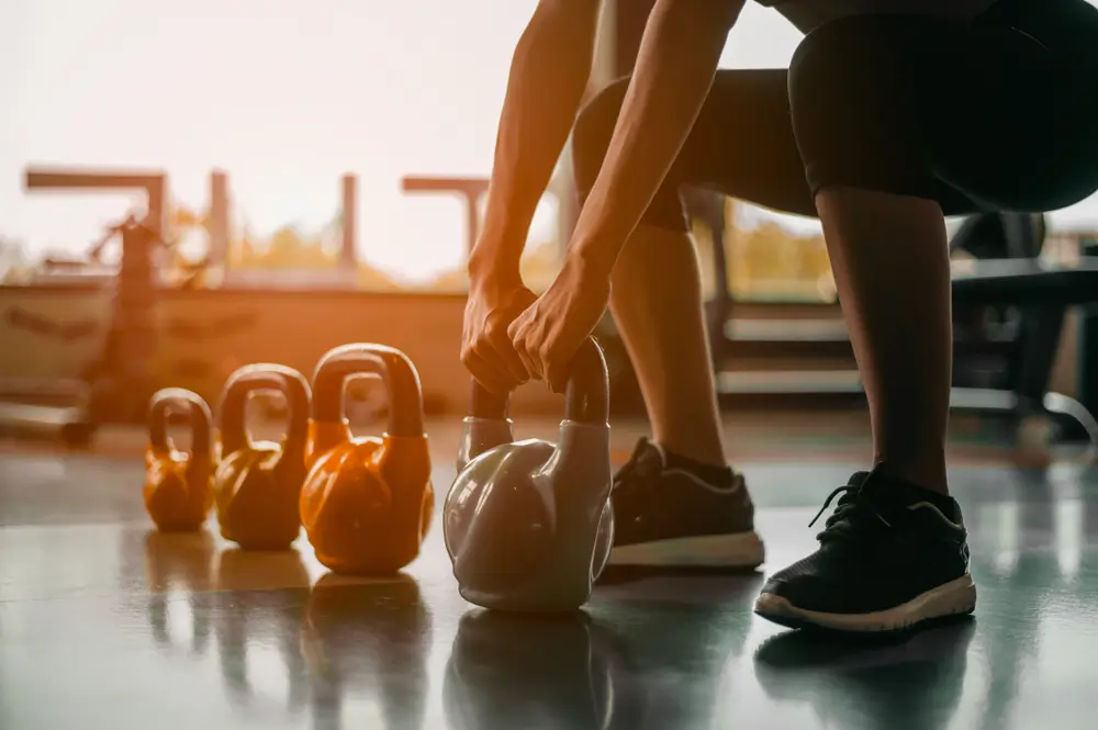 Woman in exercise gear standing in a row holding dumbbells during an exercise class at the gym.