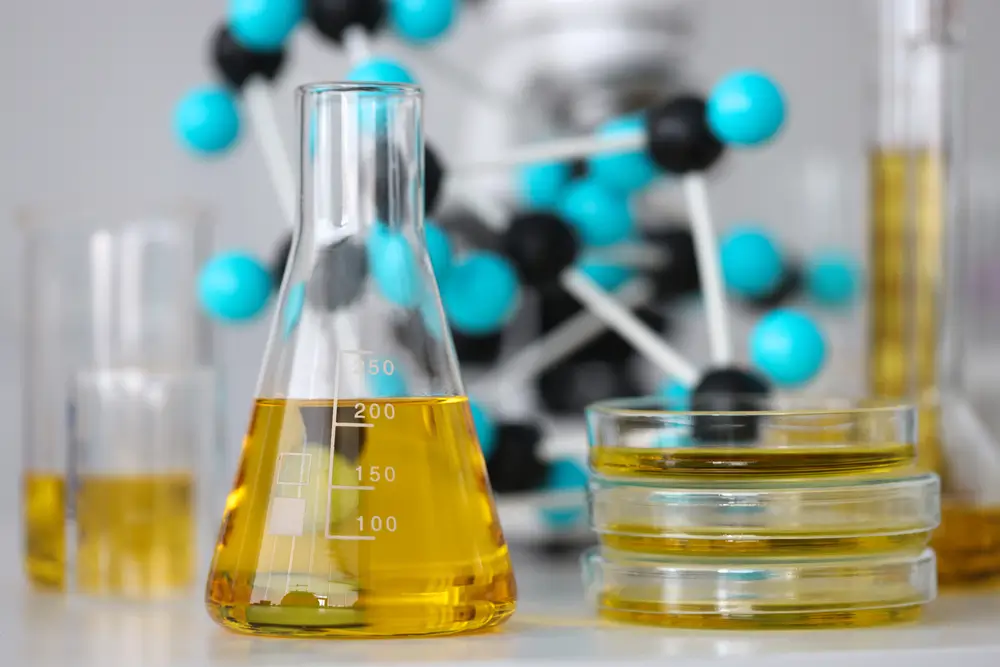 Glass test tubes with yellow viscous liquid stand on table in chemical laboratory closeup.