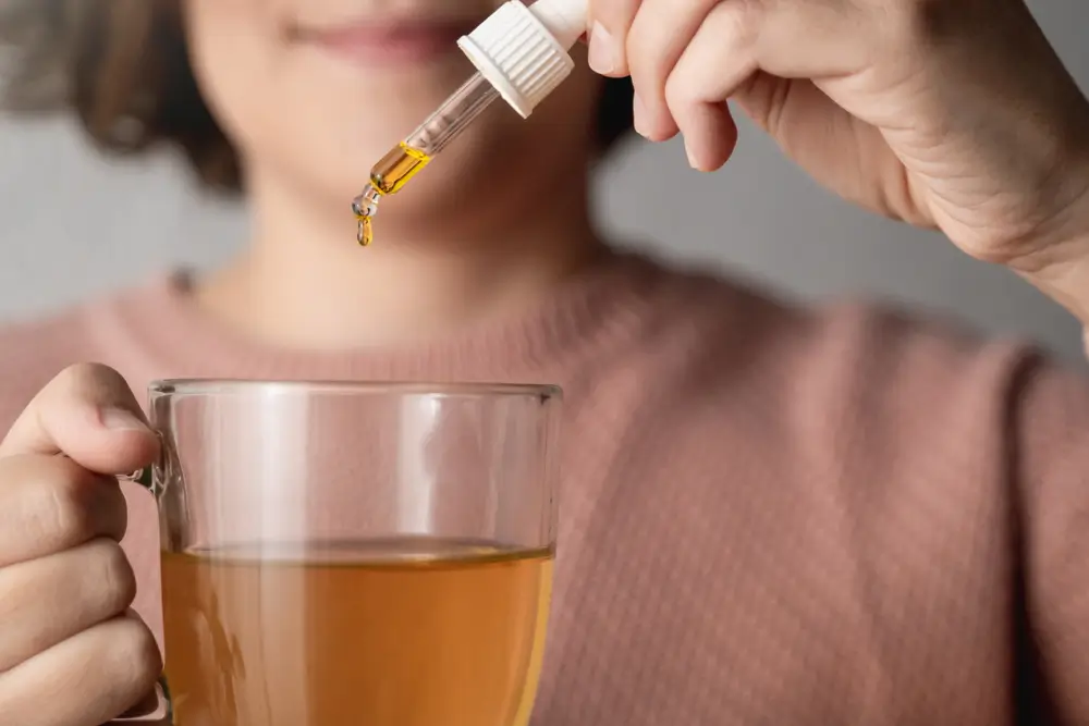 Cbd hemp oil - Woman taking cannabis oil in tea cup - Focus on drop 