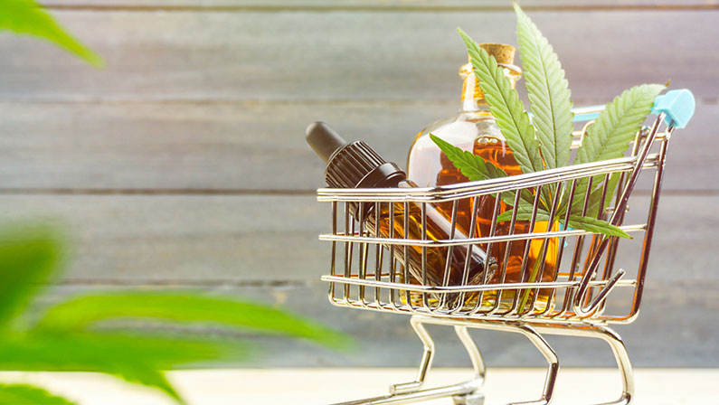Cannabis CBD oil shopping concept, Medical marijuana oils in miniature shopping cart 