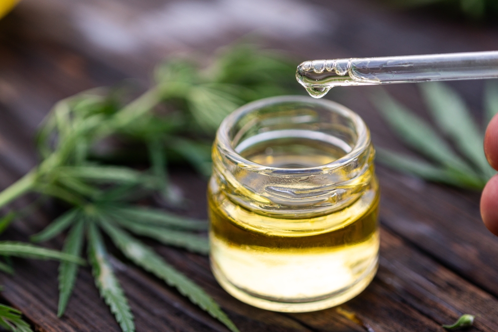 Yellow oil drips into glass bottle from a pipette. Cosmetic oil.